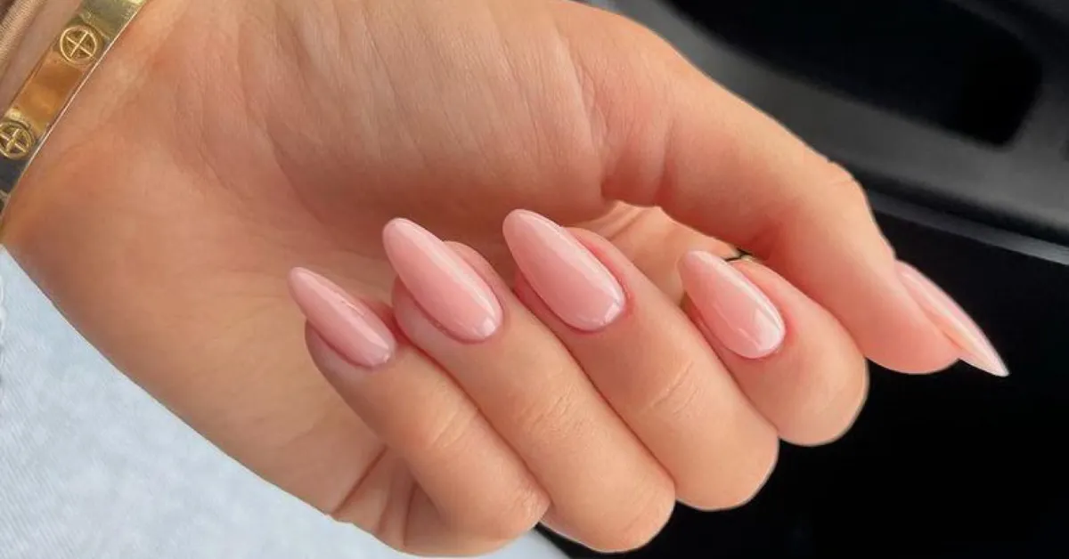 Hand with light pink glossy almond-shaped nails.